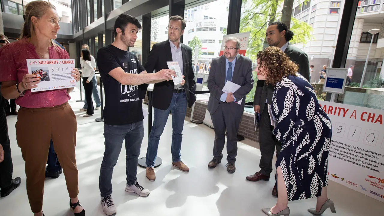 Idris overhandigt de petitie Give solidarity a chance aan Tweede Kamerleden