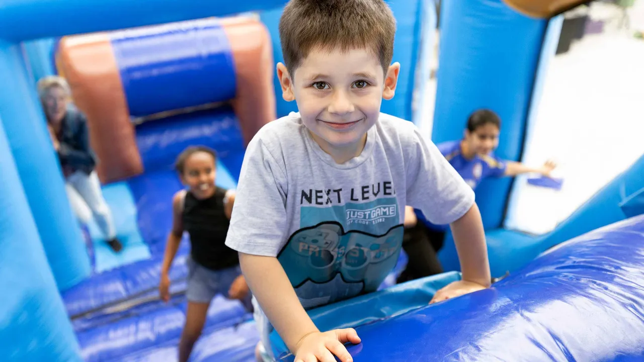 Habib klautert op het luchtkasteel tijdens het kindervakantiefestival in de noodopvang