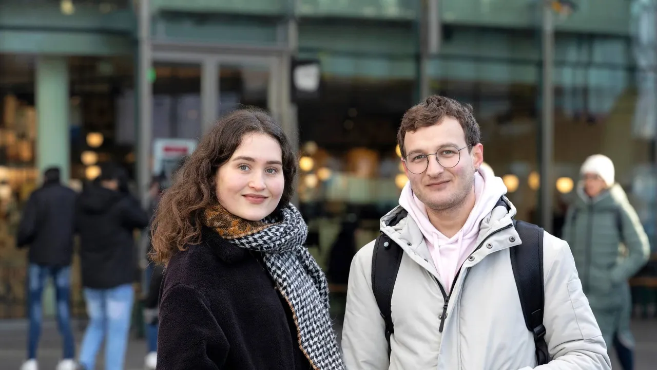 Een jonge man en vrouw kijken in de camera - coverbeeld jaarverslag VluchtelingenWerk 2023 