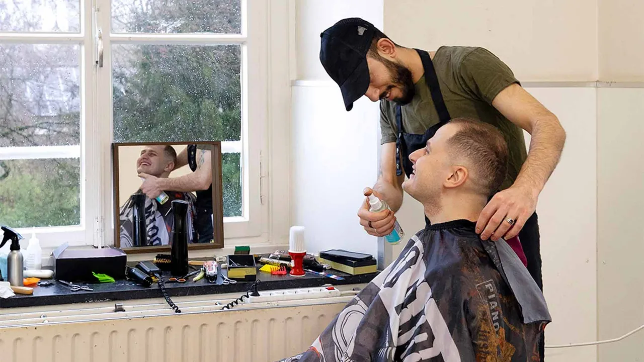 Anas wordt geknipt door de lokale kapper in het azc Baexem