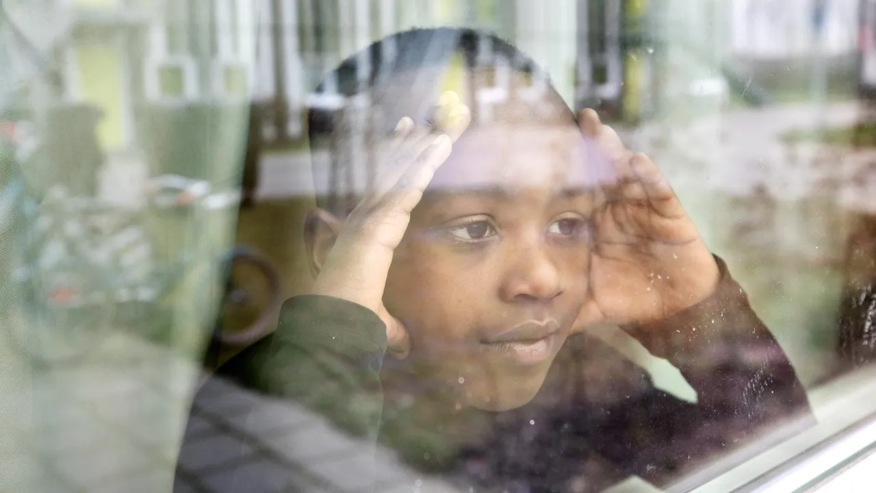 Jongen kijkt uit het raam van de opvang in Drachten