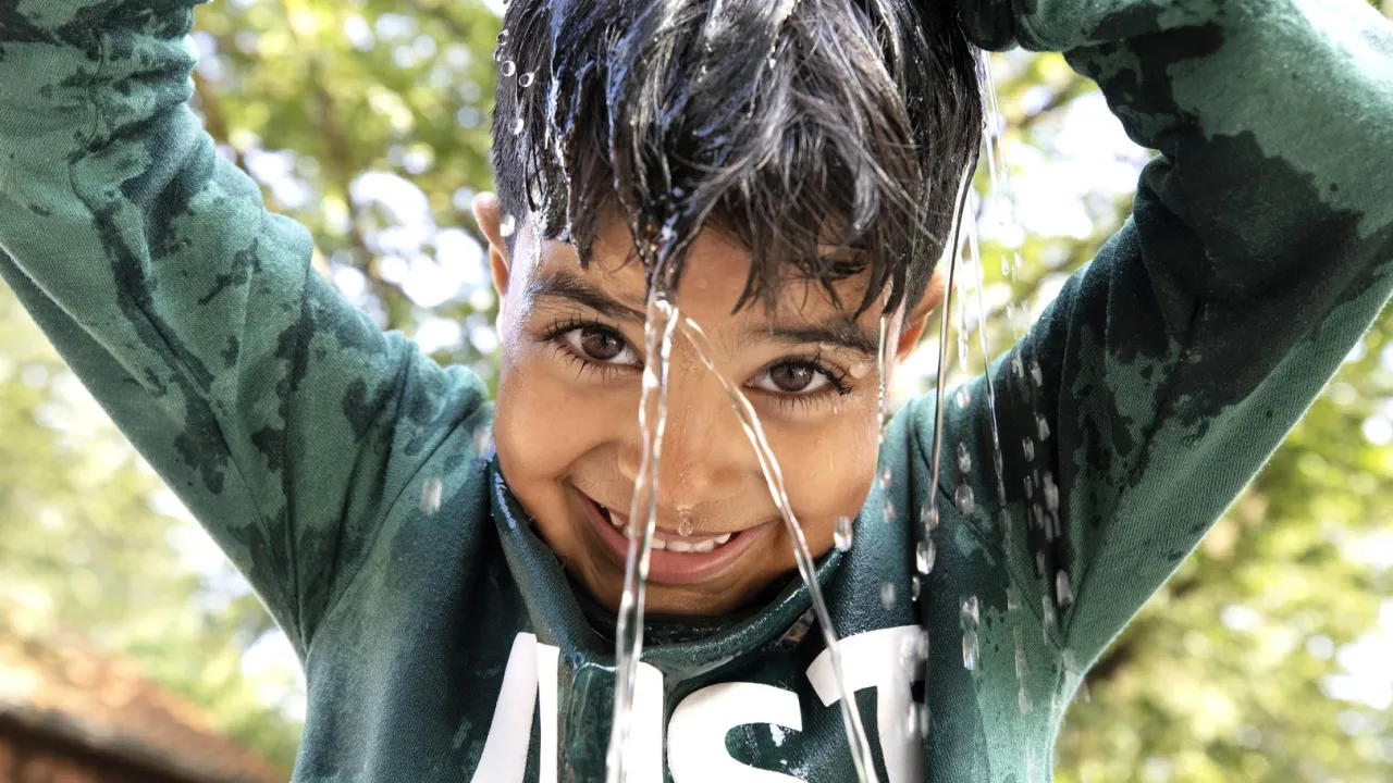 Jongen speelt met water tijdens de Kindervakantieweken