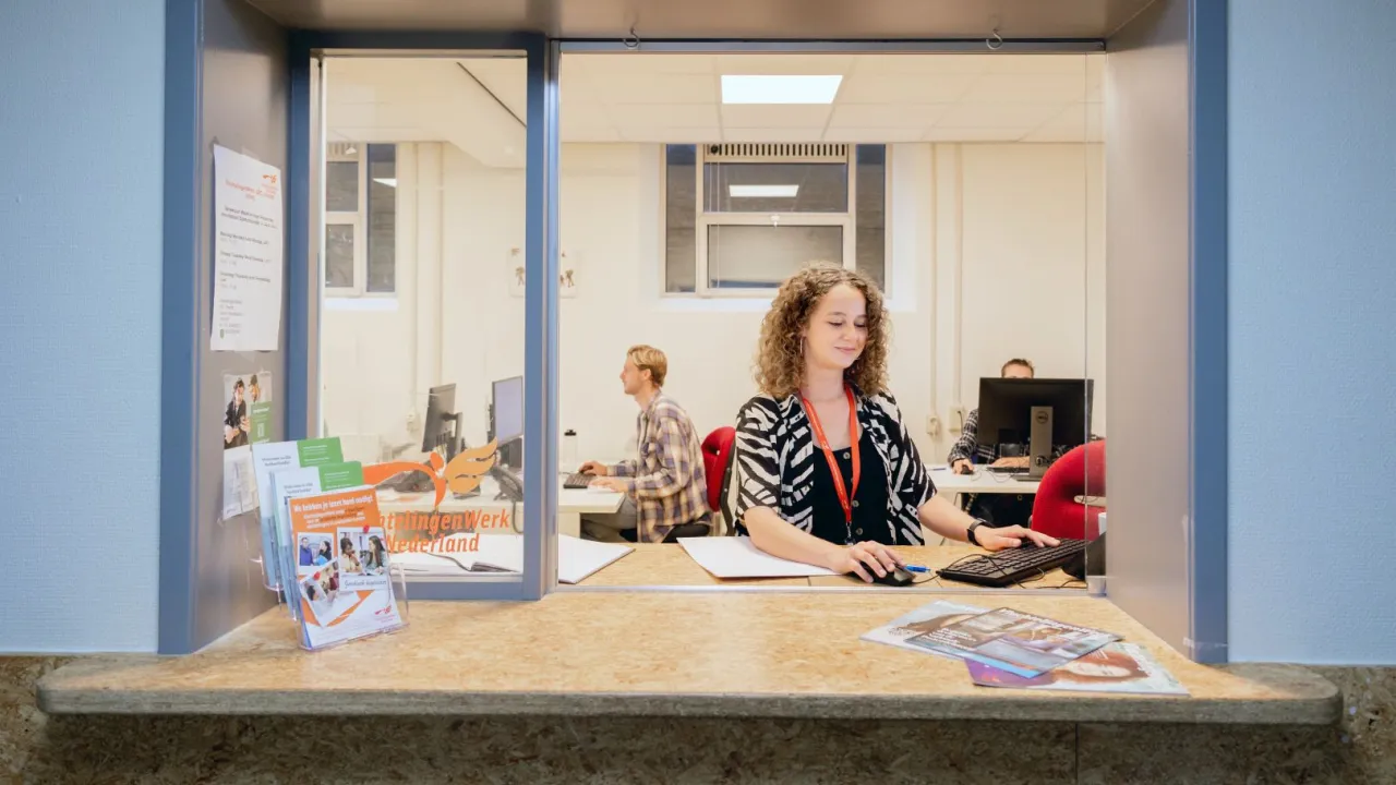 Een vrijwilliger achter de balie van VluchtelingenWerk in azc in Utrecht