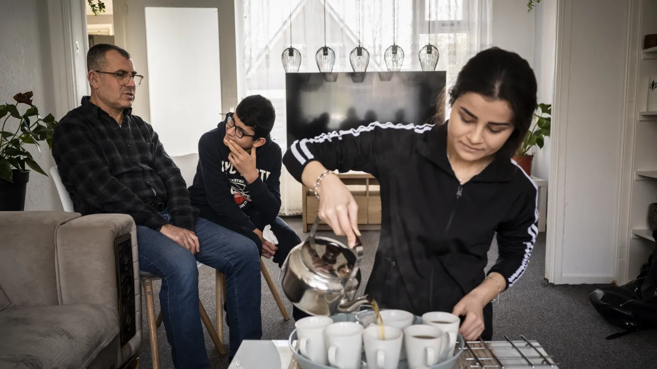 Hervestiger Afira schenkt thee in voor familie