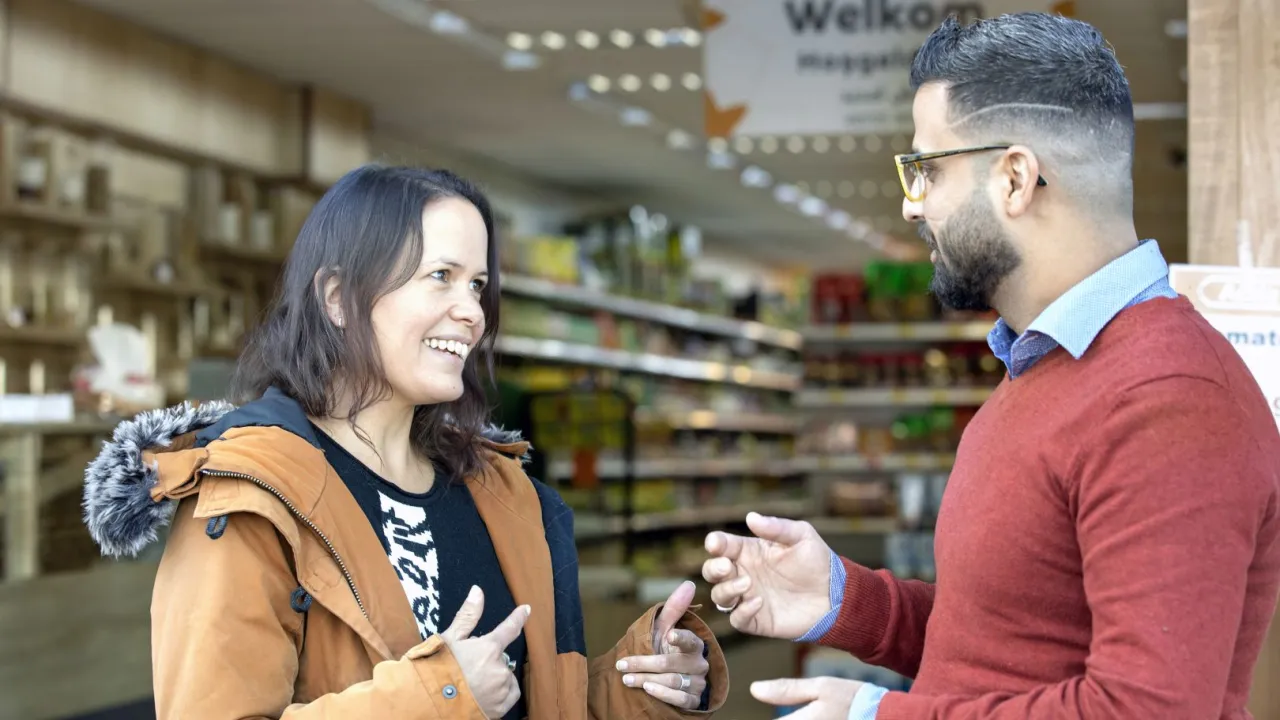 Man en vrouw staan in winkel te praten