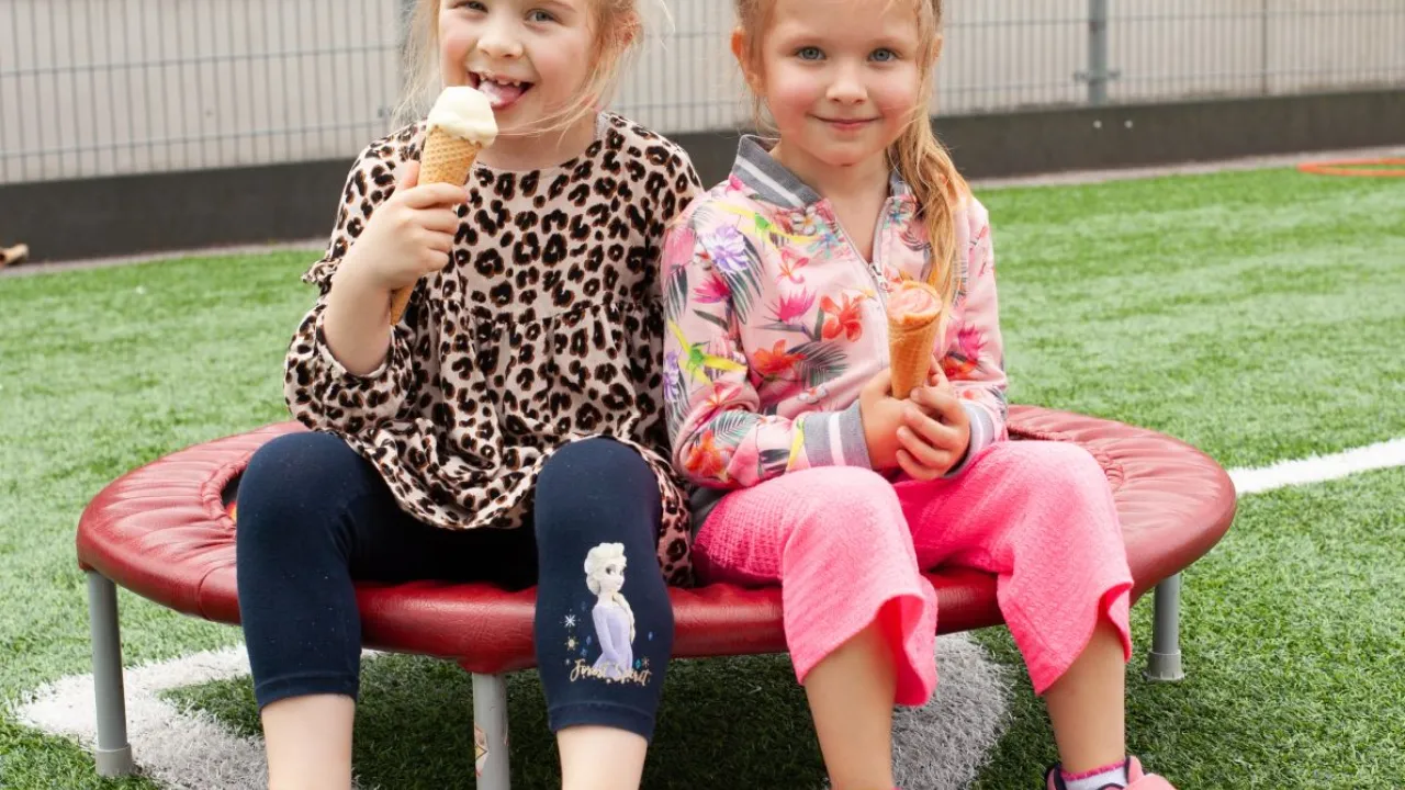 Twee meisjes eten een ijsje tijdens het Kindervakantiefestival van VluchtelingenWerk