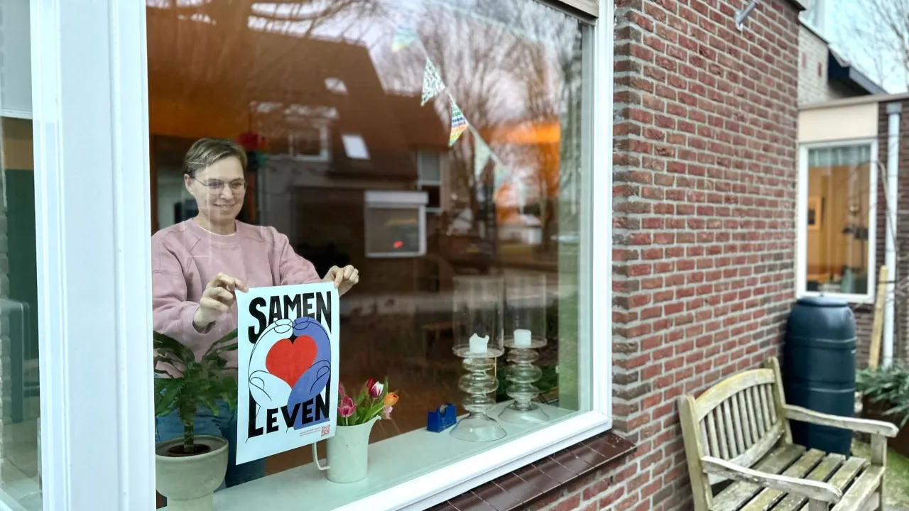 Nicole uit Houten hangt met een glimlach de Samen Leven-poster op haar raam. 