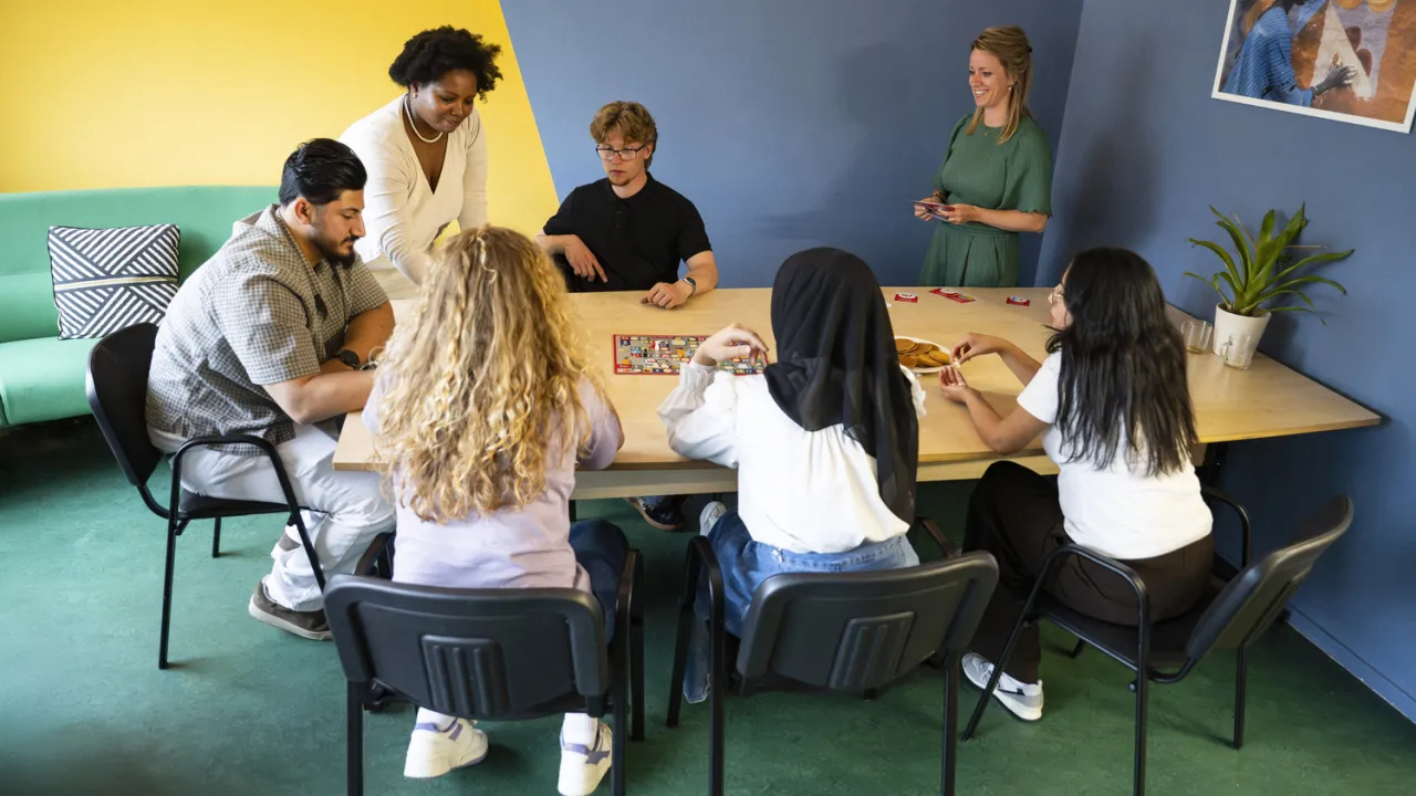 Jongvolwassen vluchtelingen doen een spel aan tafel tijdens de Geldgids-training