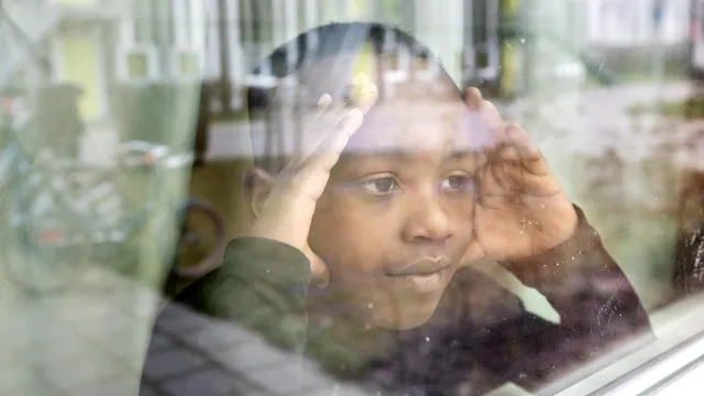 Jongen kijkt uit het raam van de opvang in Drachten