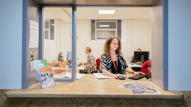 Een vrijwilliger achter de balie van VluchtelingenWerk in azc in Utrecht