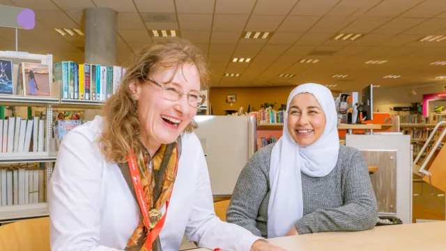 Vrijwilliger van VluchtelingenWerk in gesprek met cliënt in bibliotheek