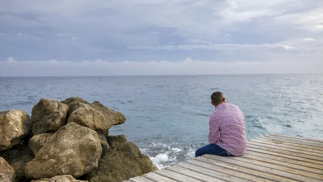 Vluchteling Sebastian kijkt uit over zee in Curacao