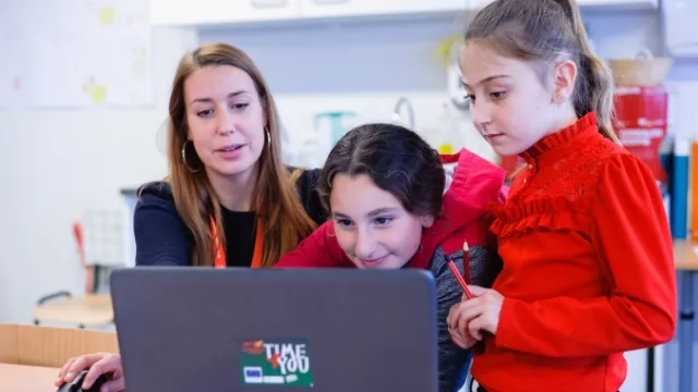 Vrijwilliger helpt vluchtelingenkinderen achter laptop