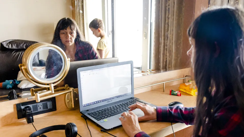Een vrouw zit achter haar laptop in een opvangboot voor Oekraïense vluchtelingen 
