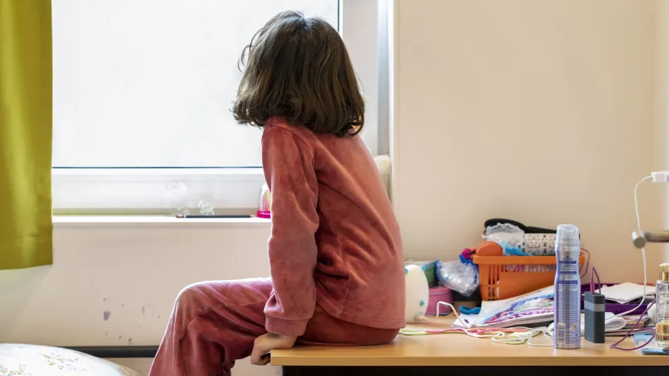 Een meisje in de opvang kijkt door het raam naar buiten