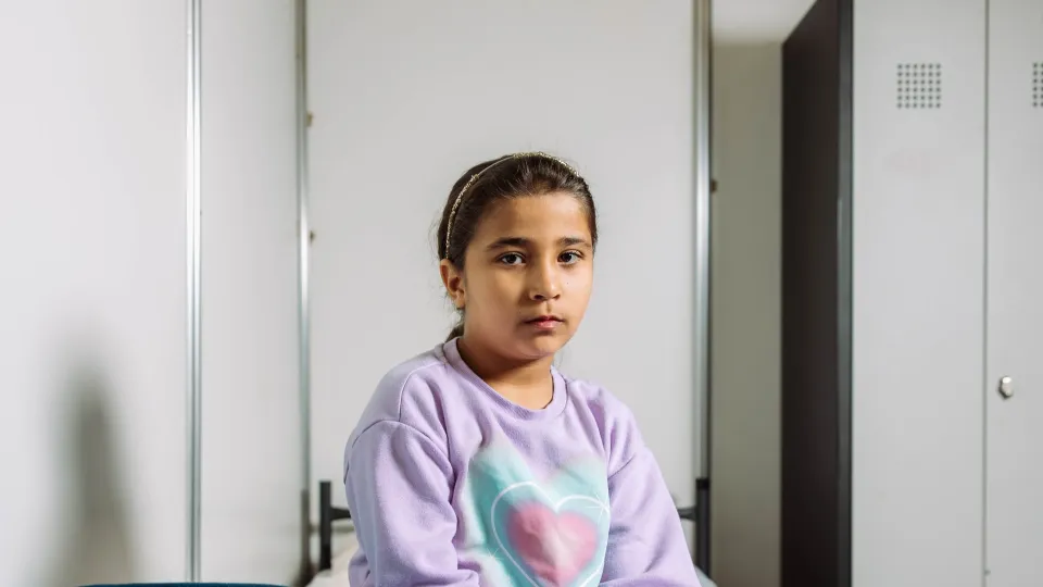 Sela zit op haar bed in de noodopvang