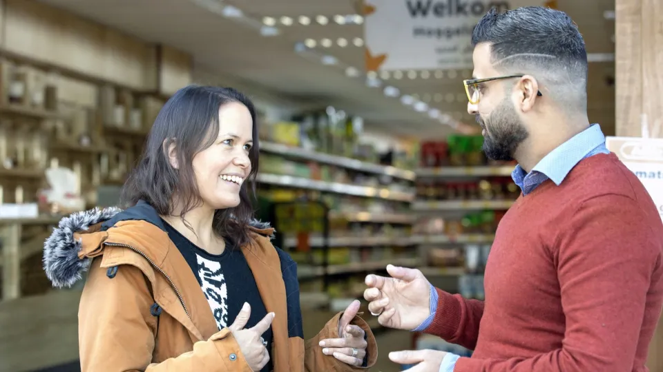 Man en vrouw staan in winkel te praten