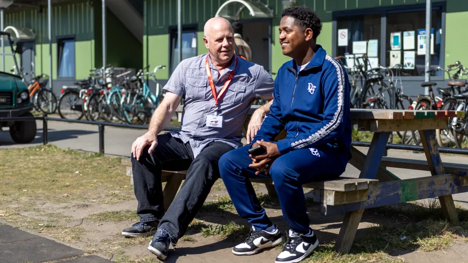 Henk met bewoner azc Harderwijk op een bankje
