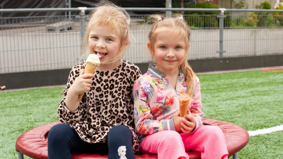 Twee meisjes eten een ijsje tijdens het Kindervakantiefestival van VluchtelingenWerk