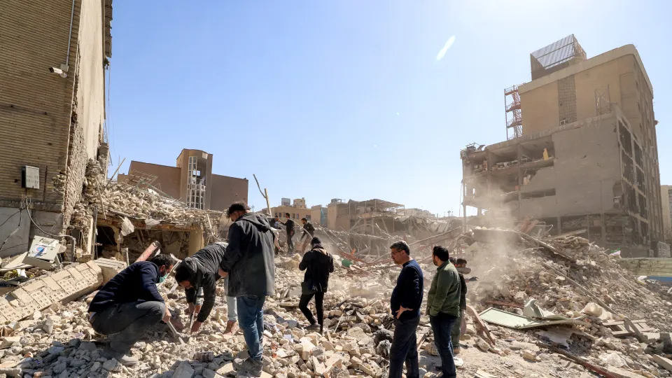 Mannen staan bij gebombardeerde woningen in Tehran, Iran
