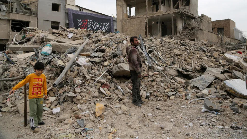 Man en kind kijken naar verwoesting gebouw in Iran, Tehran