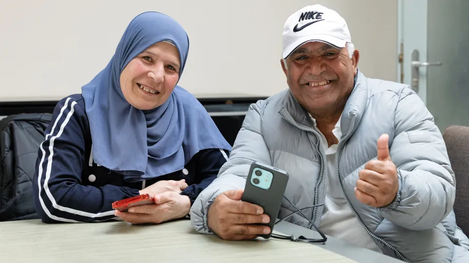 Man en vrouw zitten met telefoon in hand tijdens training DigiKlik