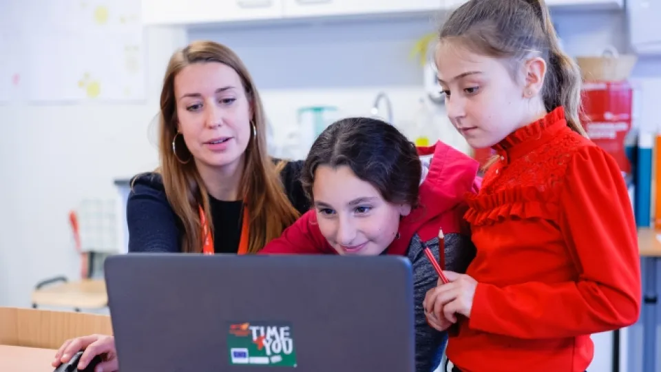 Vrijwilliger helpt vluchtelingenkinderen achter laptop