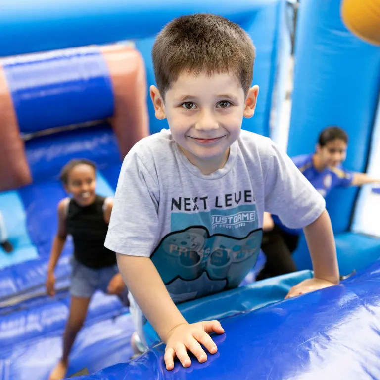Habib klautert op het luchtkasteel tijdens het kindervakantiefestival in de noodopvang
