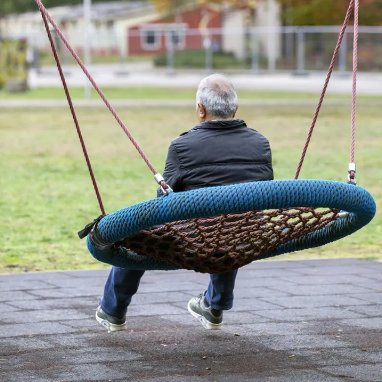 Man op schommel bij opvangplek