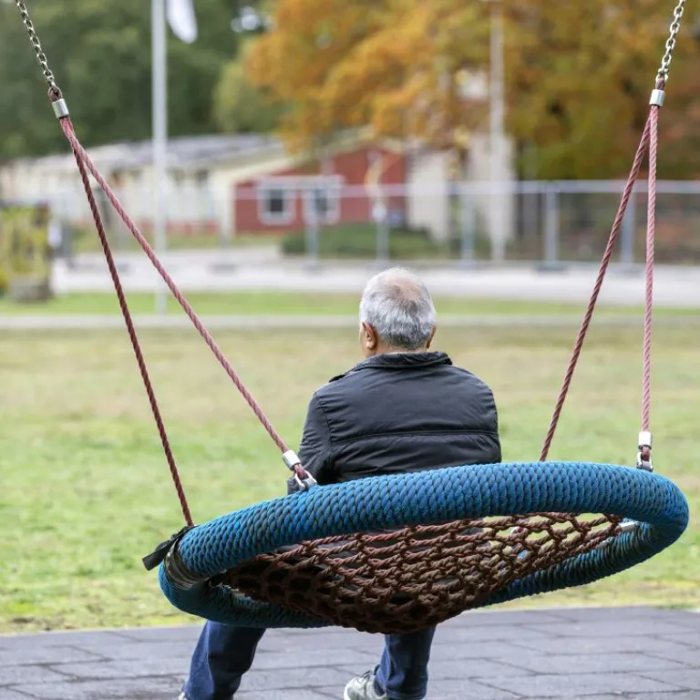 Man op schommel bij opvangplek