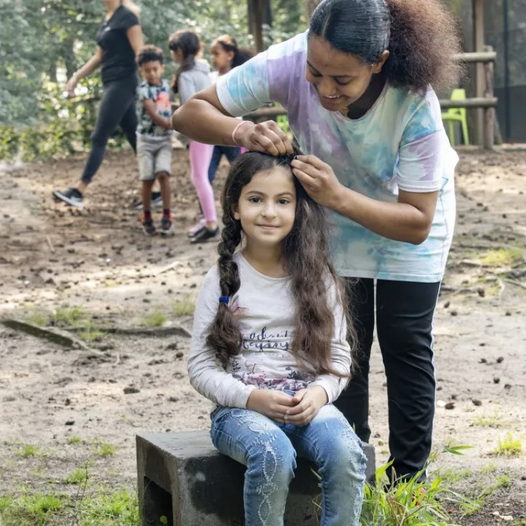 Vrijwilliger vlecht haar van meisje tijdens kindervakantieweken