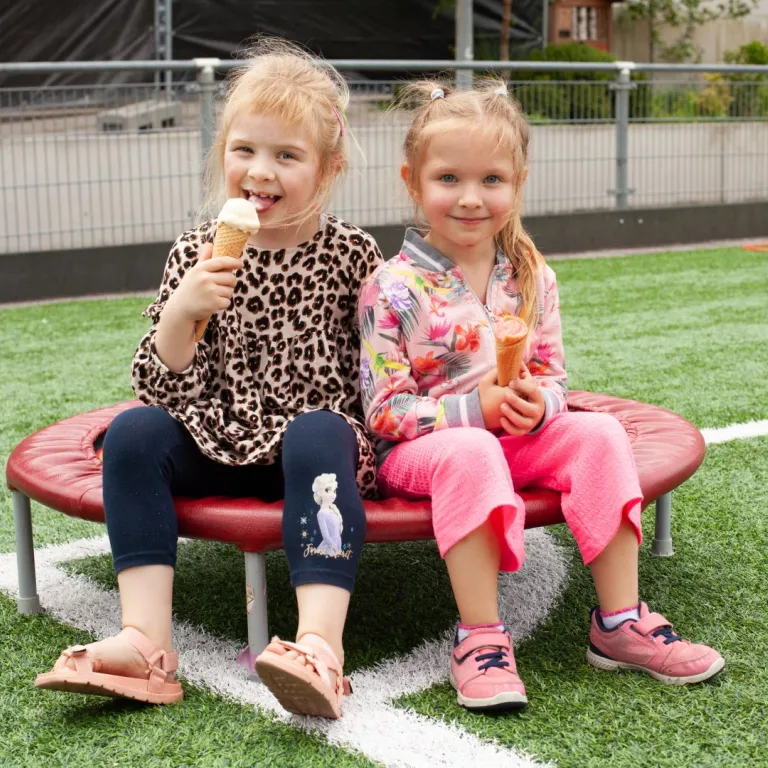 Twee meisjes eten een ijsje tijdens het Kindervakantiefestival van VluchtelingenWerk