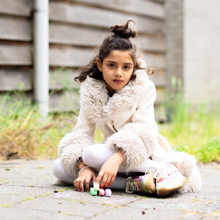Aisha speelt met stoepkrijt voor de noodopvang