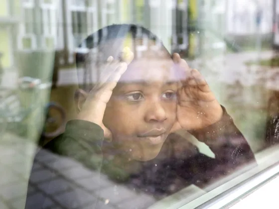 Jongen kijkt uit het raam van de opvang in Drachten