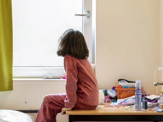 Een meisje in de opvang kijkt door het raam naar buiten