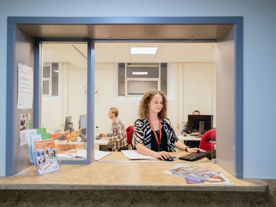 Een vrijwilliger achter de balie van VluchtelingenWerk in azc in Utrecht