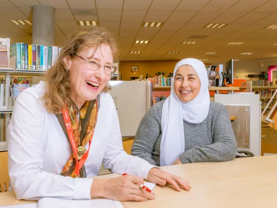 Vrijwilliger van VluchtelingenWerk in gesprek met cliënt in bibliotheek