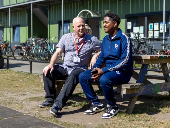 Henk met bewoner azc Harderwijk op een bankje