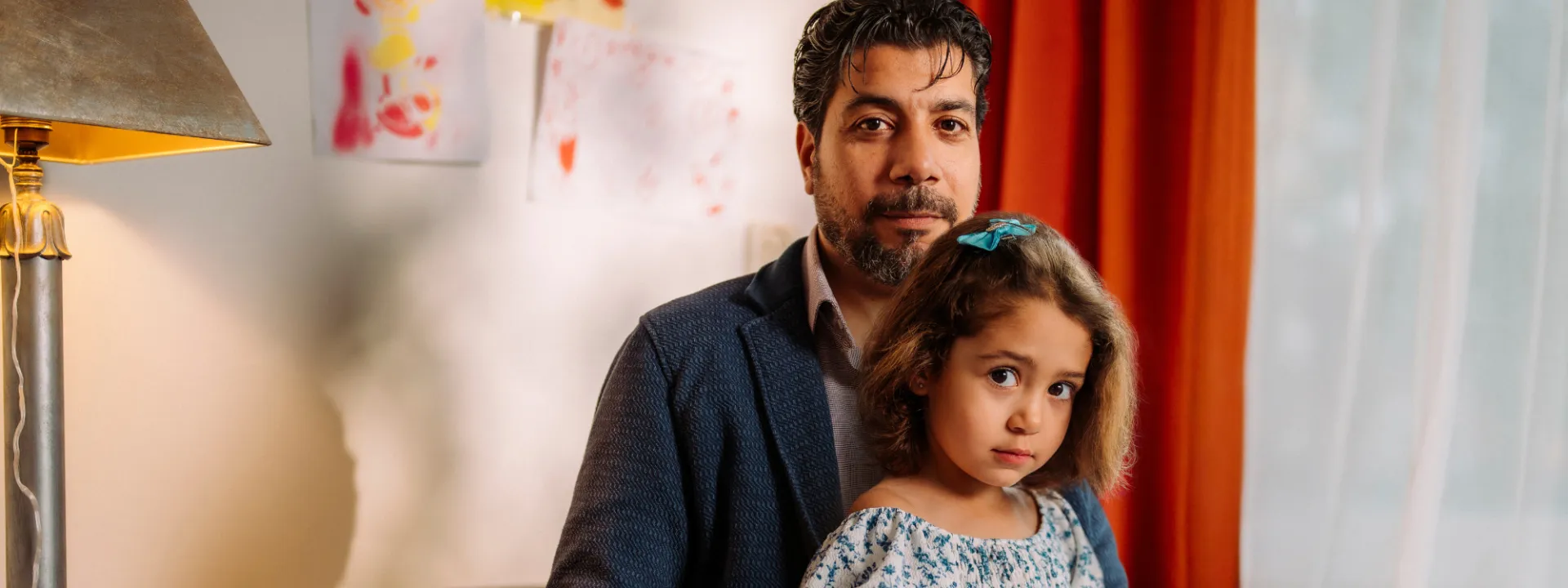 Nizar zit op bed met dochter