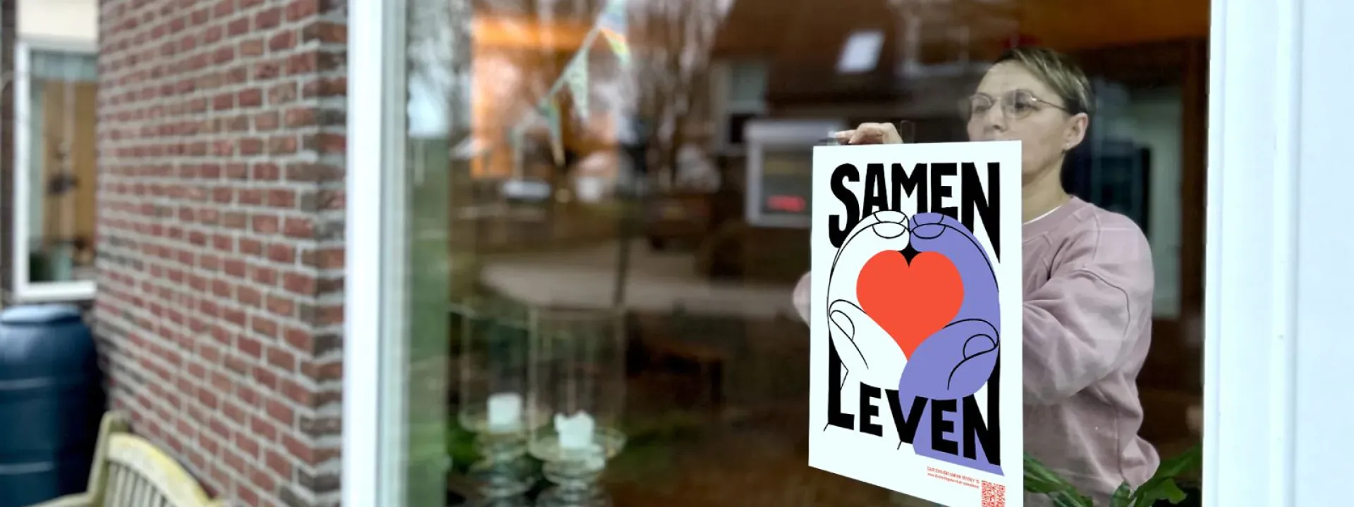 Vrouw hangt vluchtelingenwerk poster voor het raam