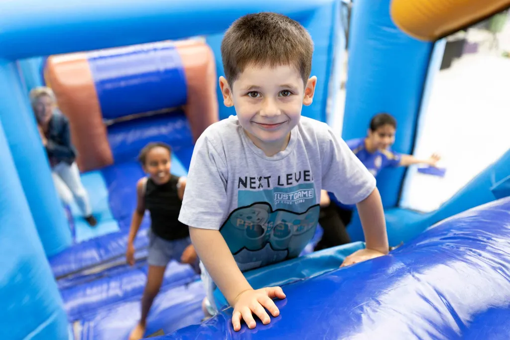 Habib klautert op het luchtkasteel tijdens het kindervakantiefestival in de noodopvang