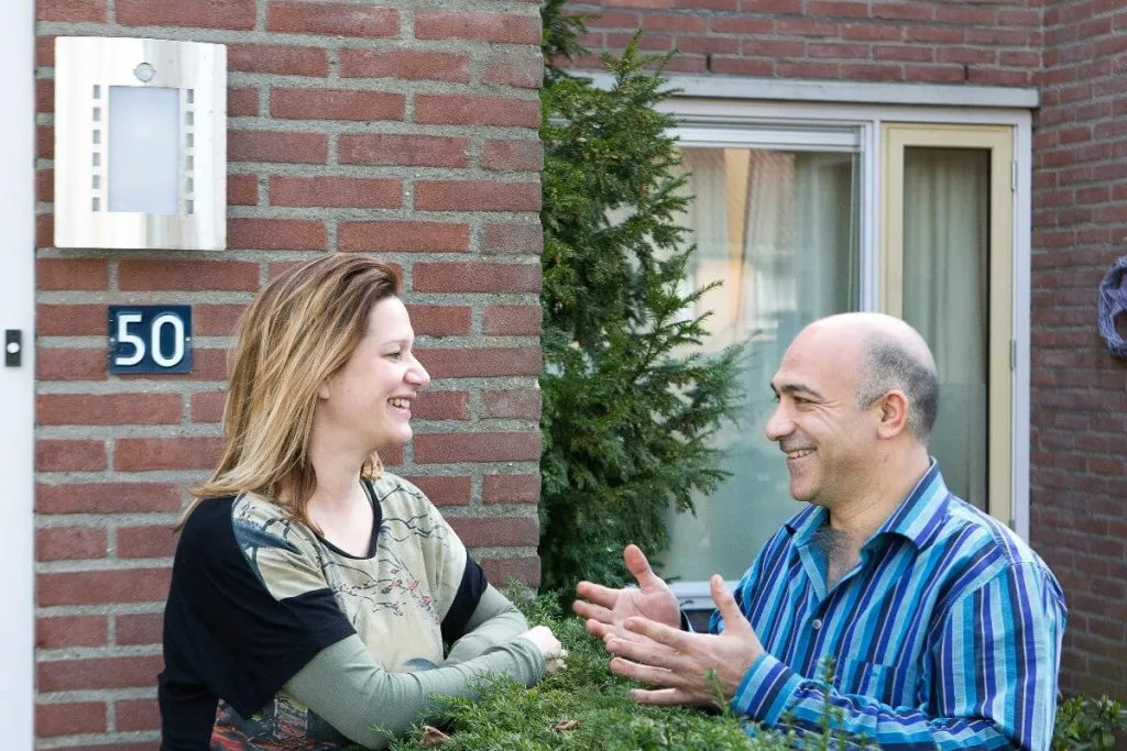 Buren voeren gesprek over een heg