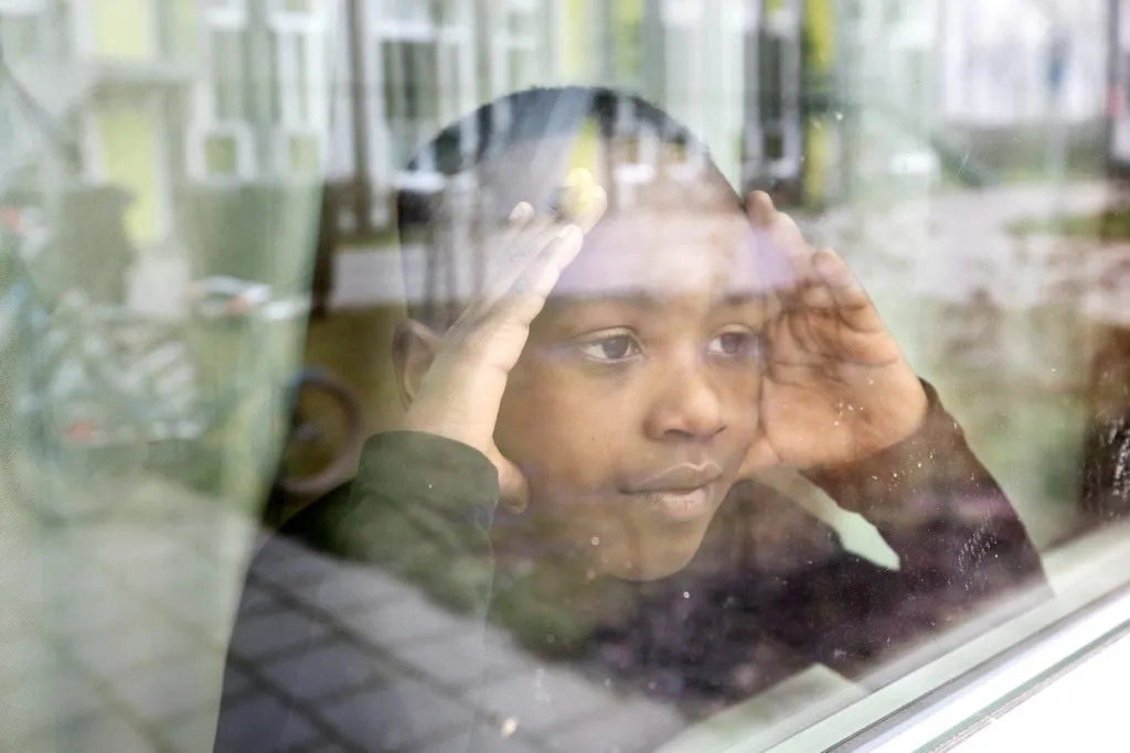 Jongen kijkt uit het raam van de opvang in Drachten