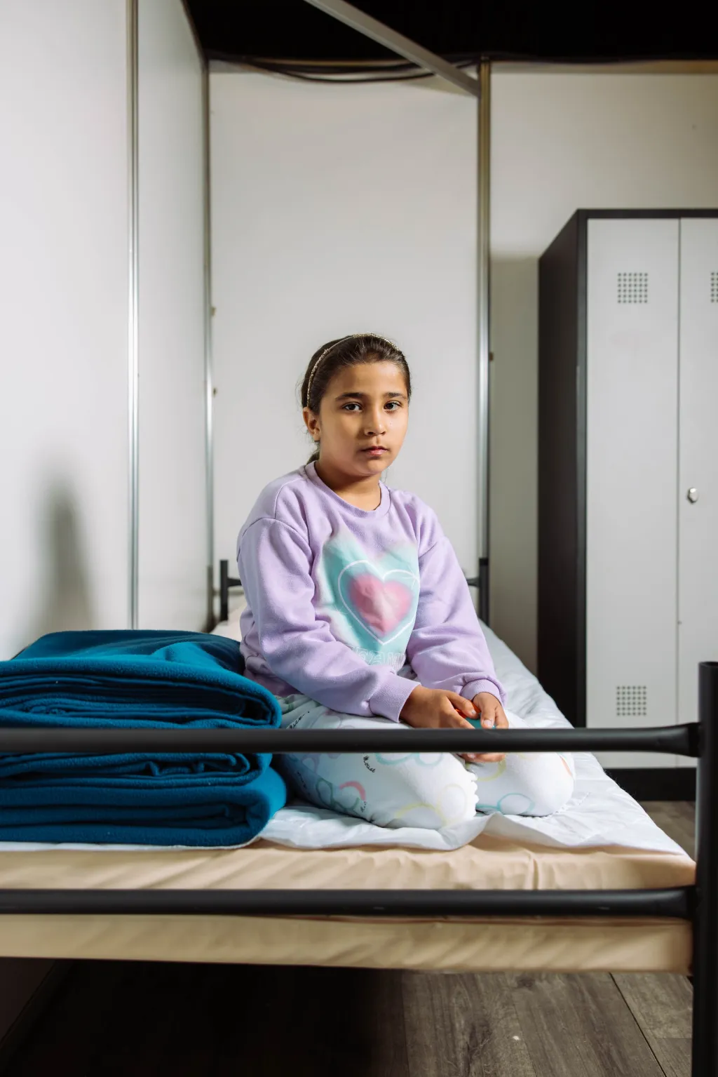 Sela zit op haar bed in de noodopvang