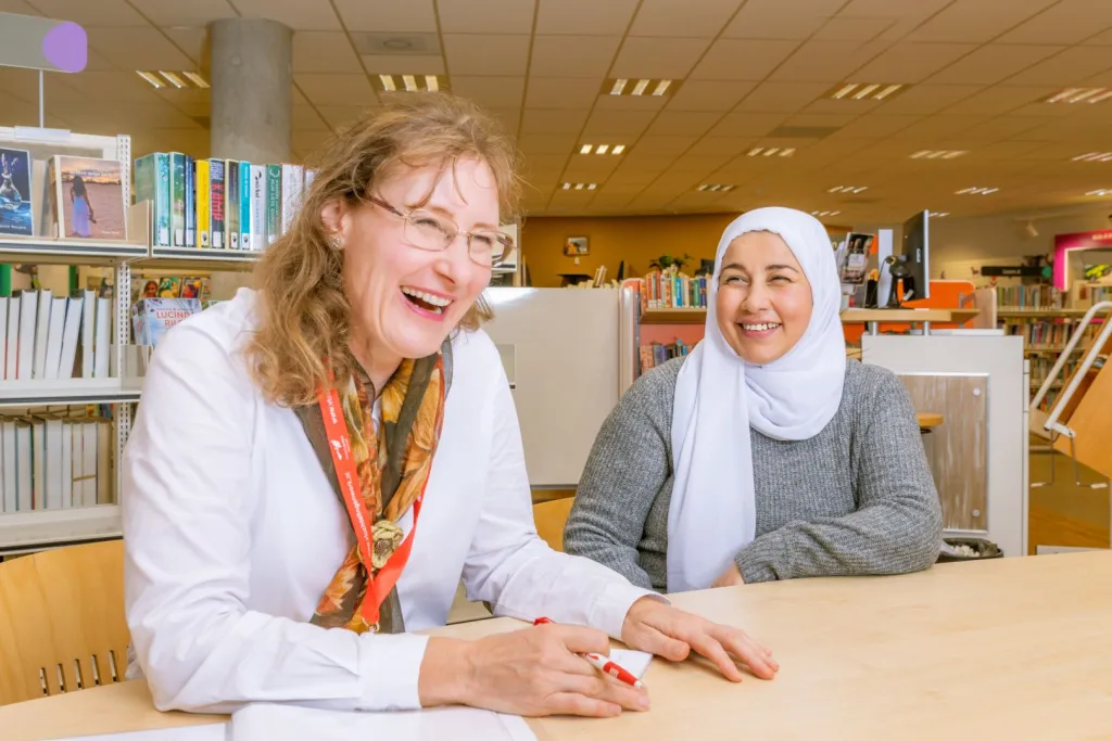 Vrijwilliger van VluchtelingenWerk in gesprek met cliënt in bibliotheek