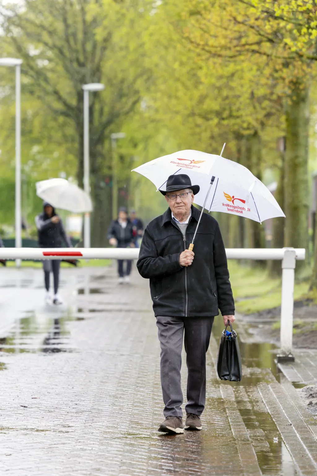 Vrijwilliger Adrie met paraplu in Ter Apel