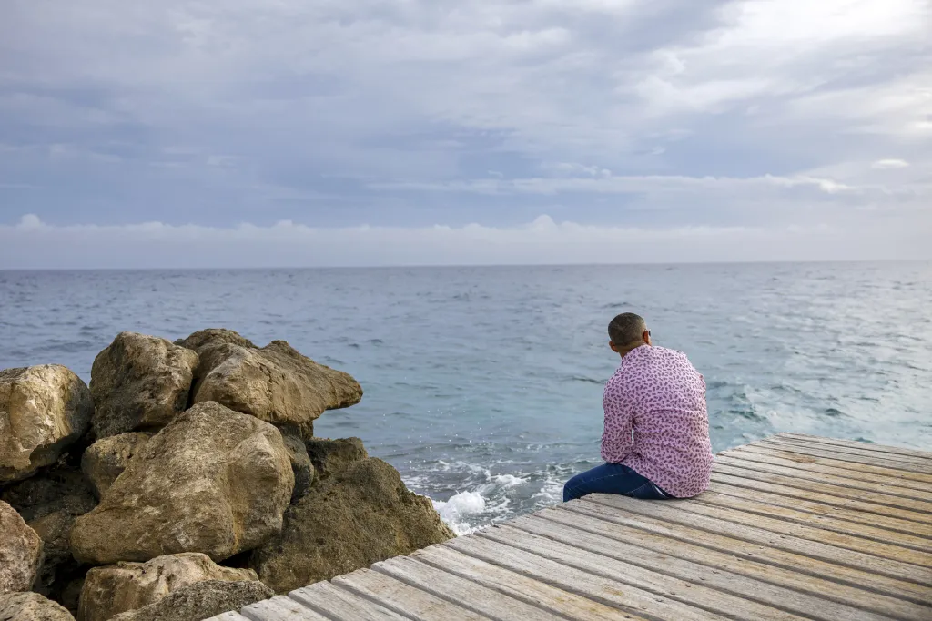 Vluchteling Sebastian kijkt uit over zee in Curacao