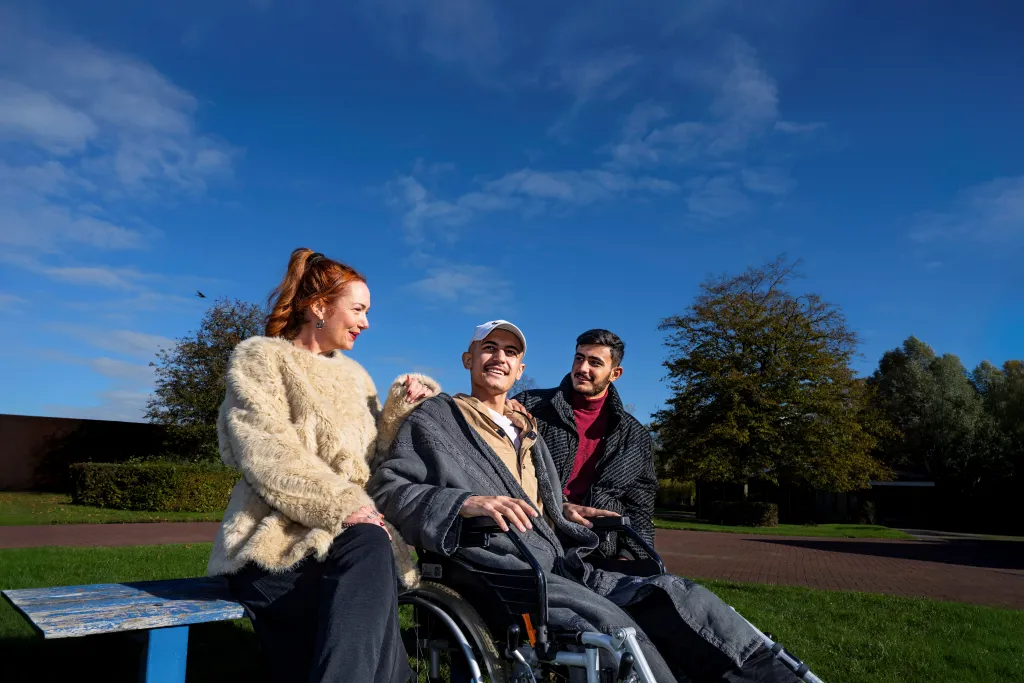 Karin Walid op een bankje met Ahmed in zijn rolstoel