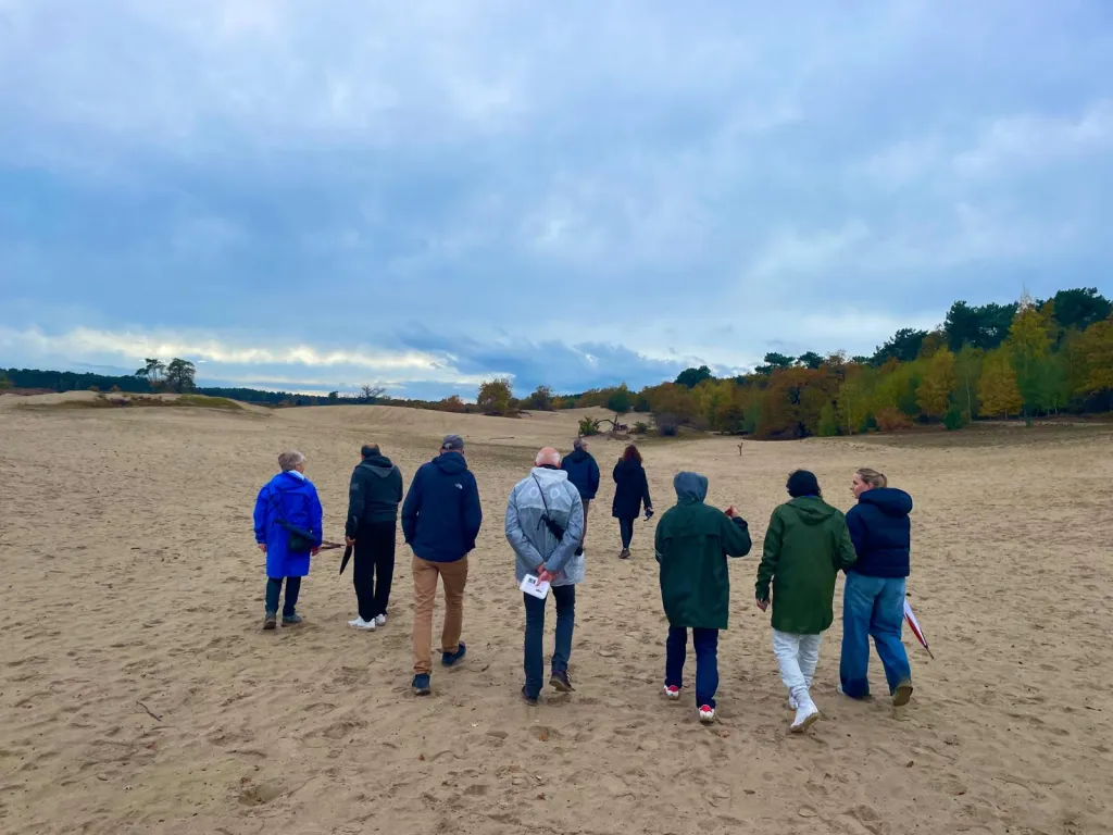 Een groep mensen die samen wandelen in de duinen van Heusden