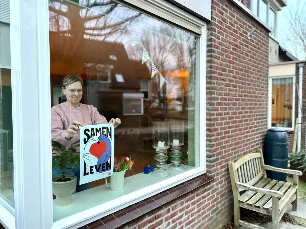 Nicole uit Houten hangt met een glimlach de Samen Leven-poster op haar raam. 